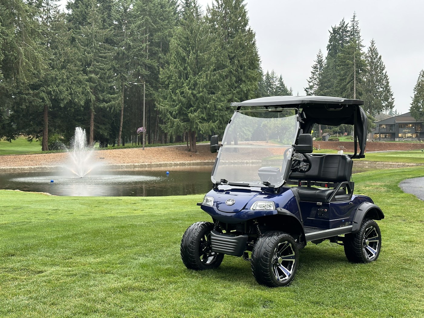 A golf cart parked beside a pond with a fountain