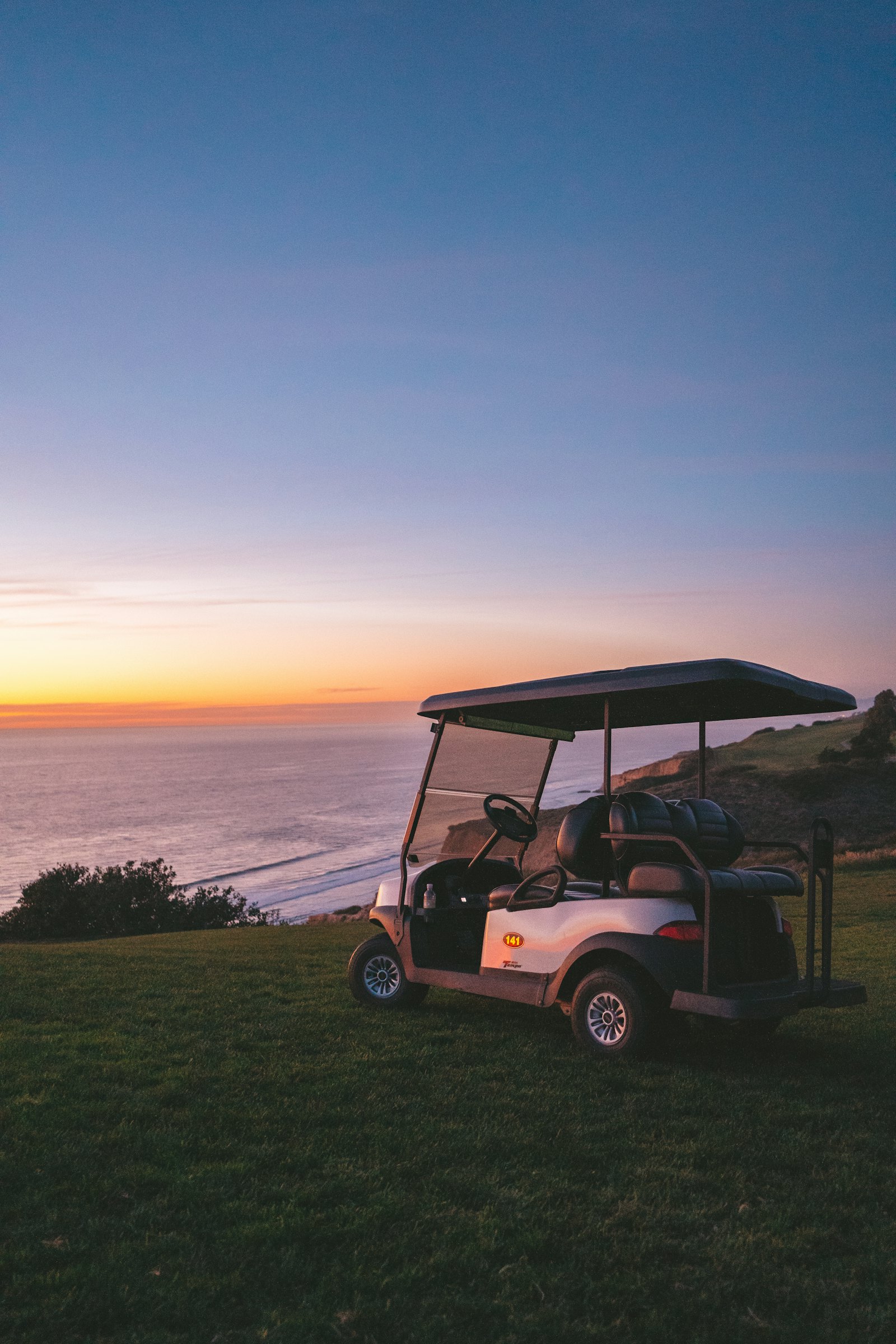 A golf cart parked above the sea at sunset